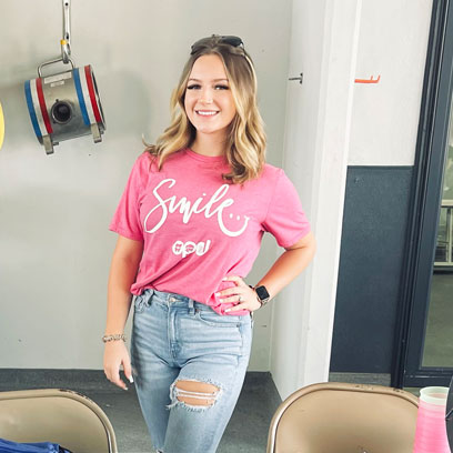 Young woman in a pink 'Smile' t-shirt smiling in the dental office