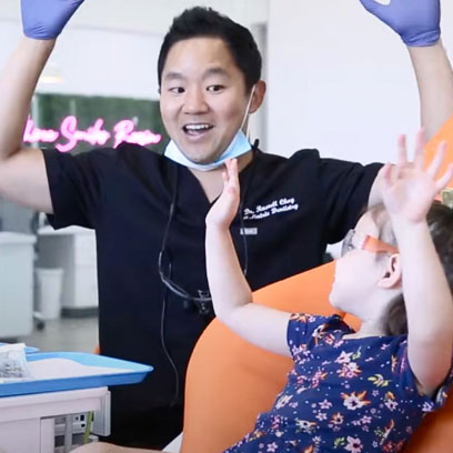 Smiling orthodontist talking with a young child in the dental office